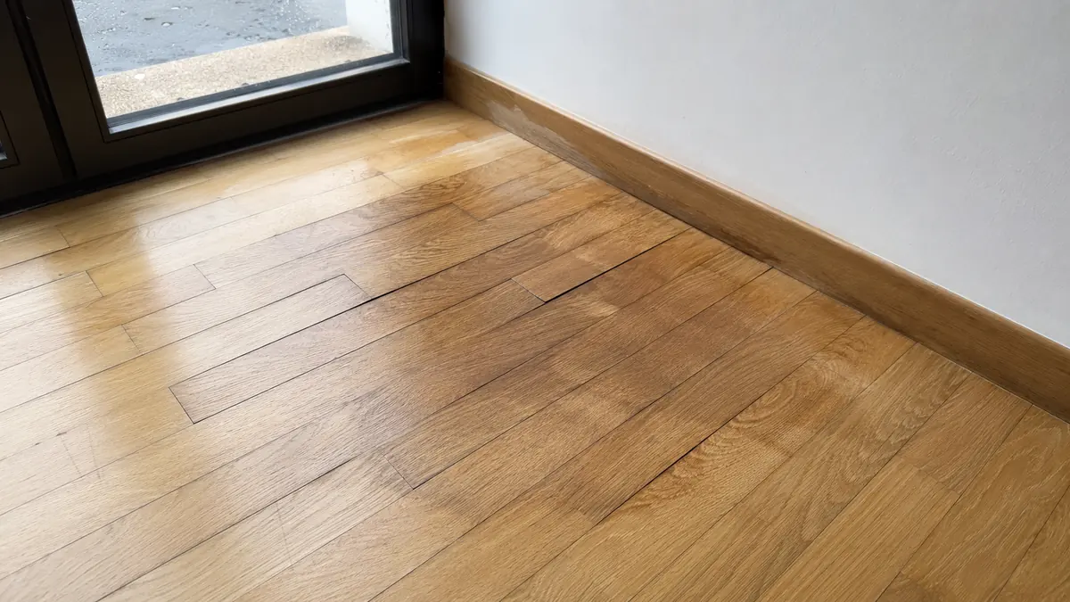 Parquet deformado y oscurecido por humedad junto a una puerta